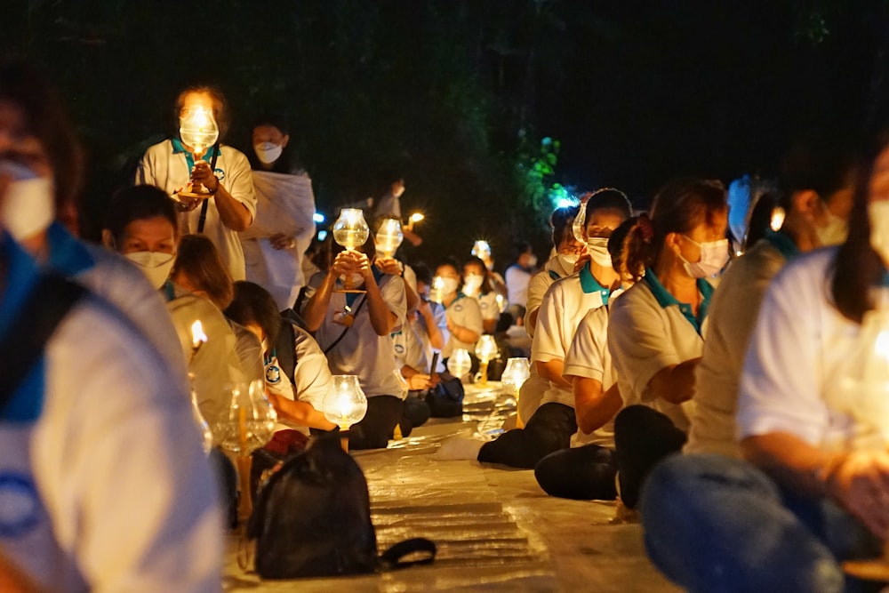 a group of people sitting on the ground holding candles