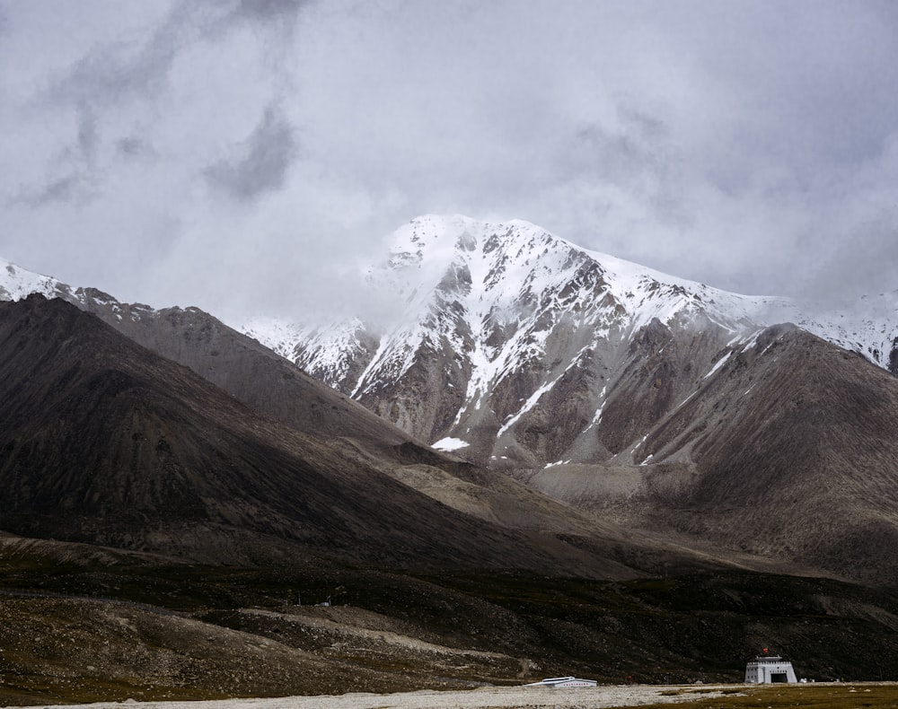 a snowy mountain range with a house in the foreground