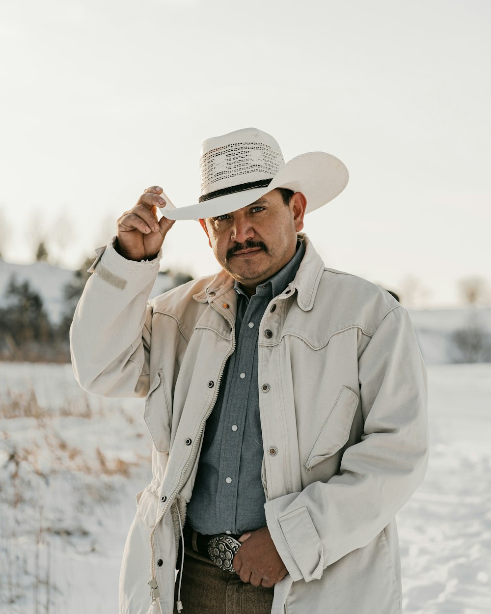 a man in a white hat and jacket standing in the snow