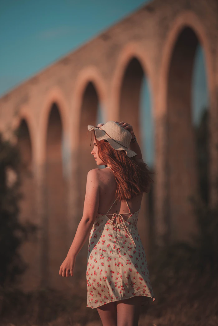 Woman in a dress and hat walking away from the camera