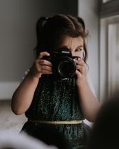 A little girl holding a camera up to her face 