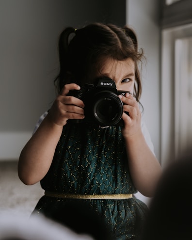 A little girl holding a camera up to her face 