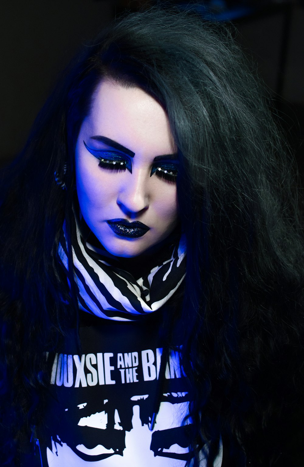 a woman with long black hair and blue makeup