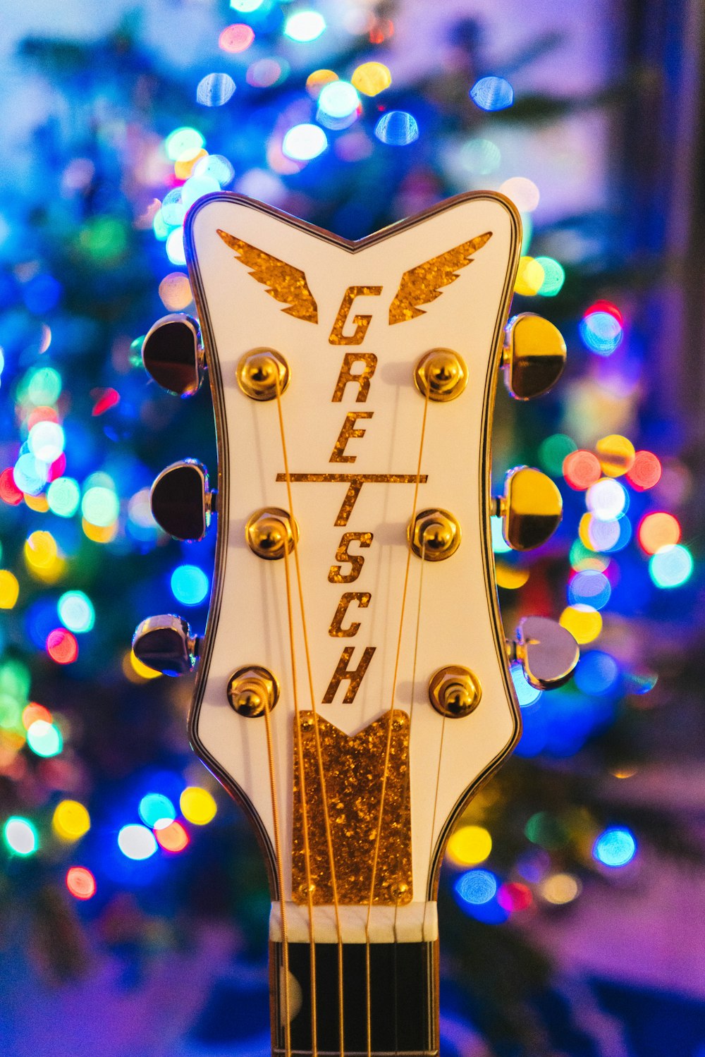 a close up of a guitar with a christmas tree in the background