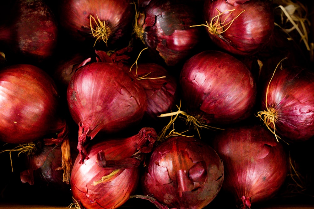 a pile of red onions sitting on top of a wooden table