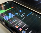 A smartphone screen displays a battery usage graph with blue and green bars indicating activity levels over time. The screen shows detailed information about screen time, including hours and minutes, as well as app usage such as YouTube, Instagram, Teams, and Safari.