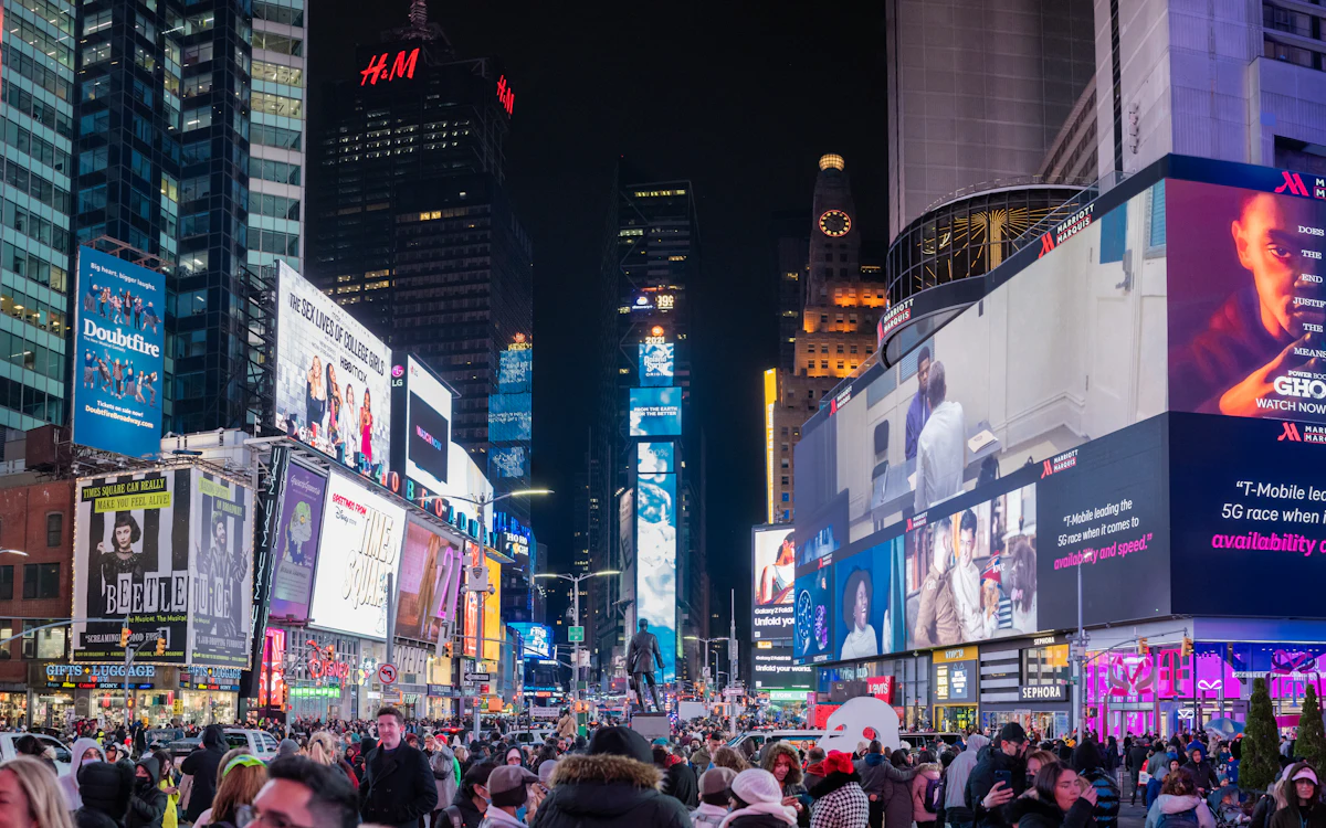 Times Square illuminated at night with bustling crowds and glowing billboards