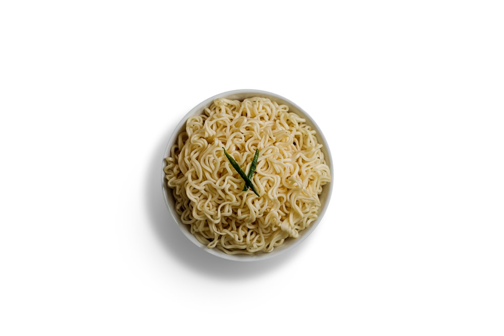 a bowl of ramen noodles with a green twig sticking out of it