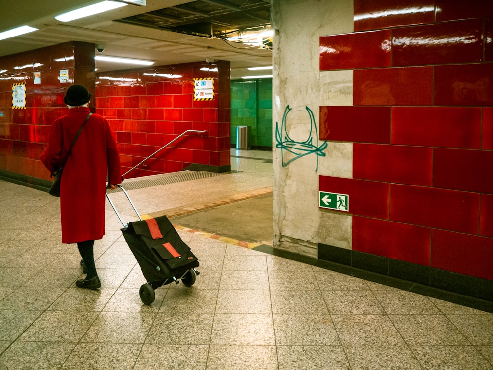 a man in a red coat pulling a black suitcase