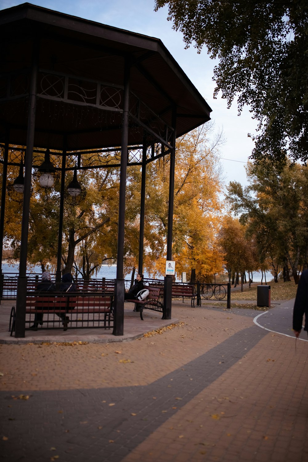 a gazebo in a park with people walking around