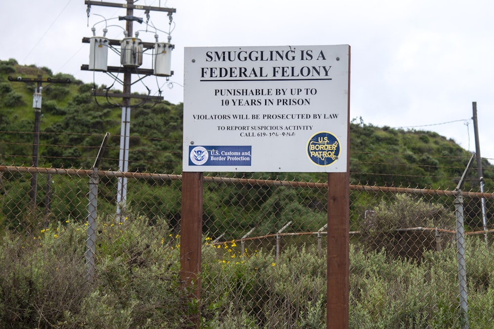 a sign is posted on a fence near a field