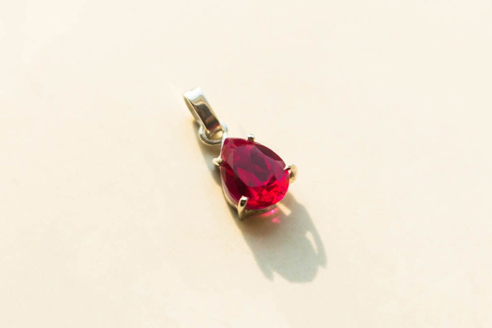 a red heart shaped pendant sitting on top of a table