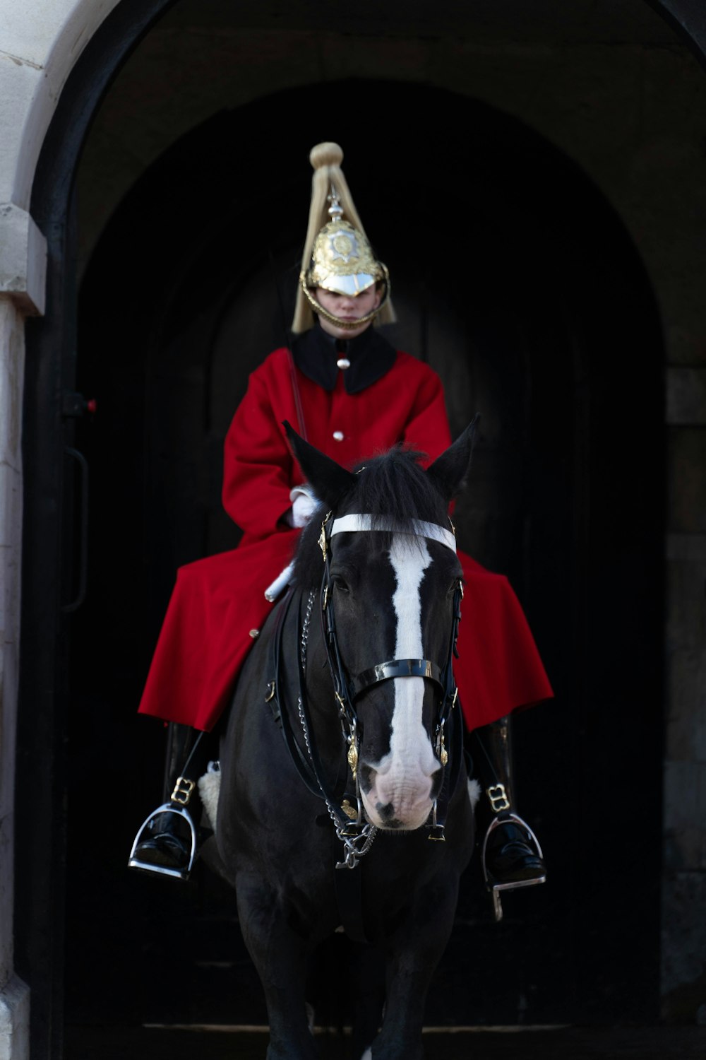 a man in a red coat riding a black horse