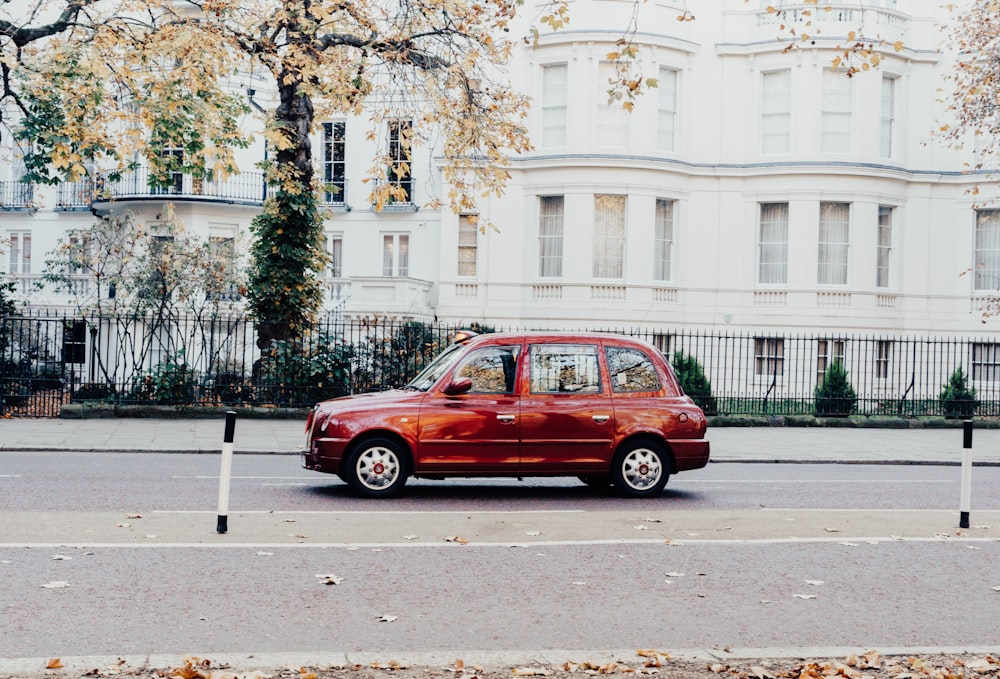 a red car driving down a street next to a tall white building