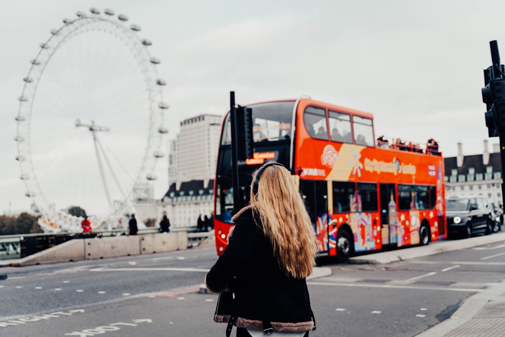 a woman standing in front of a red double decker bus