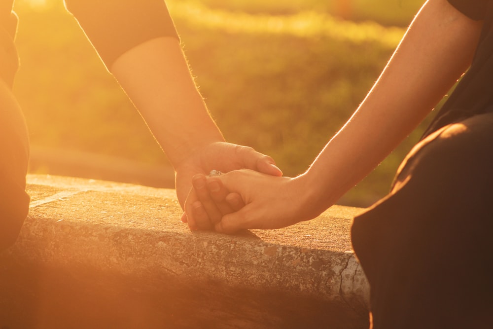 a close up of two people holding hands