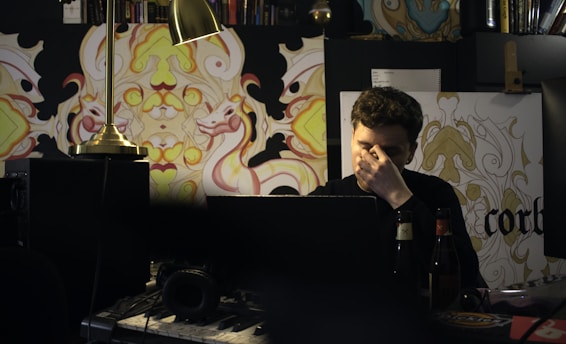 A thoughtful person sitting at a desk, surrounded by books and a laptop, contemplating social issues.