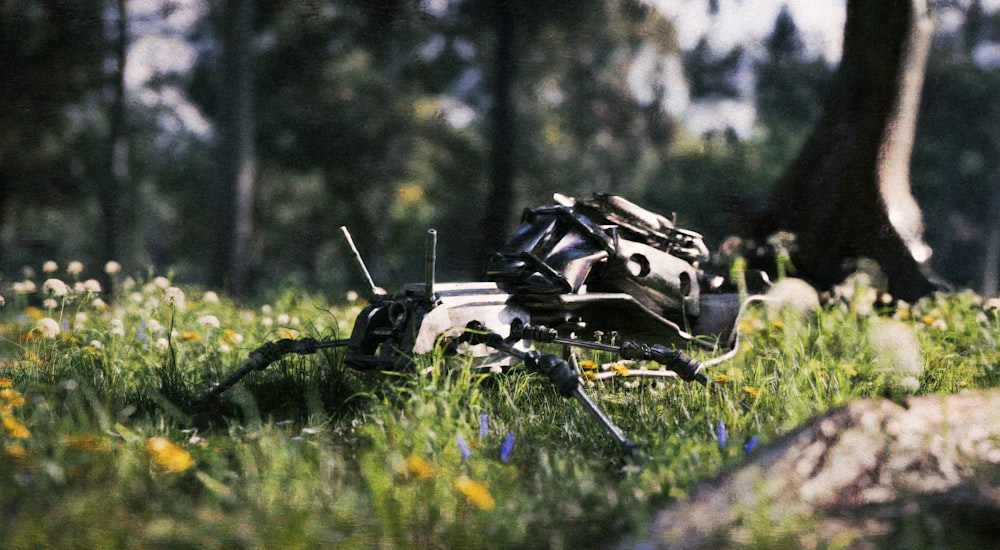 a broken motorcycle laying in the grass near a tree