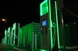 a row of green gas pumps at night