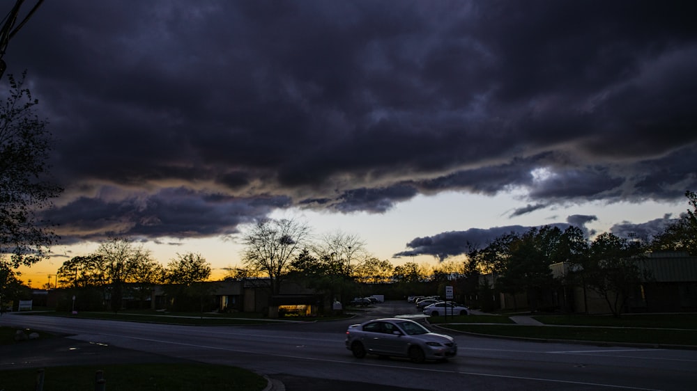 a car driving down a street under a cloudy sky