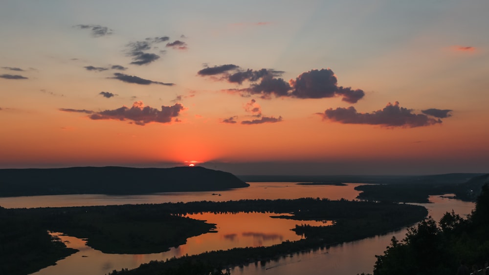 the sun is setting over a lake and mountains