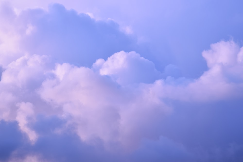 a plane flying through a cloudy blue sky