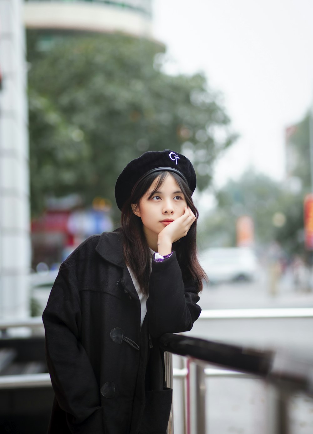 a woman leaning on a rail with her hand on her chin