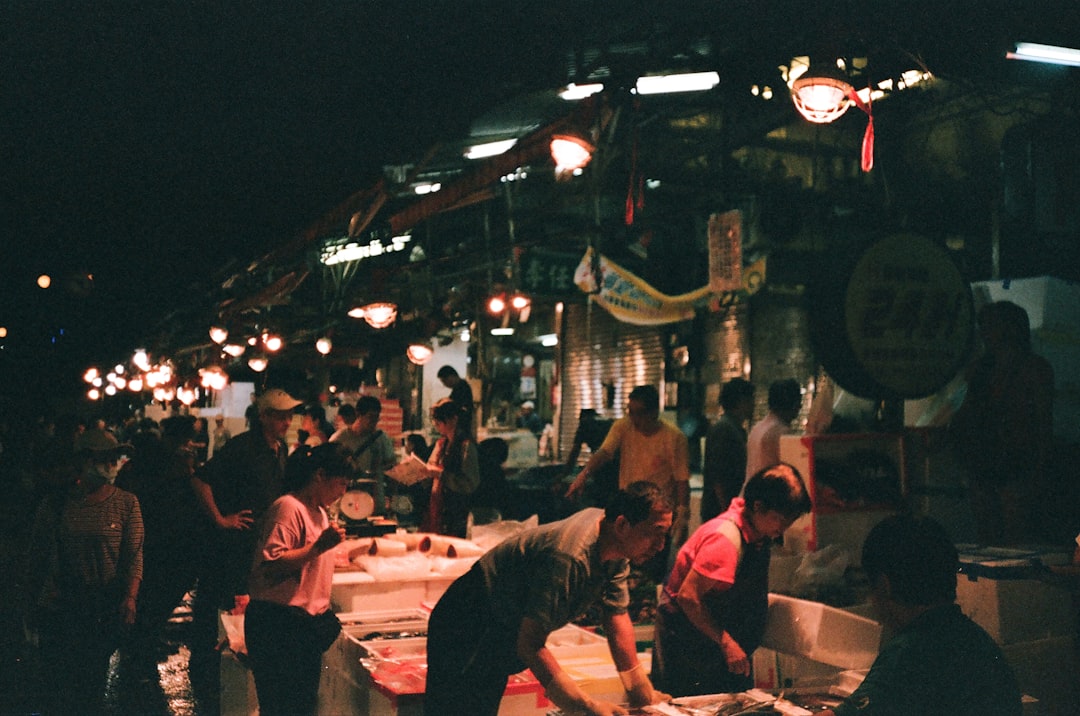 a group of people standing around a food market, Keelung