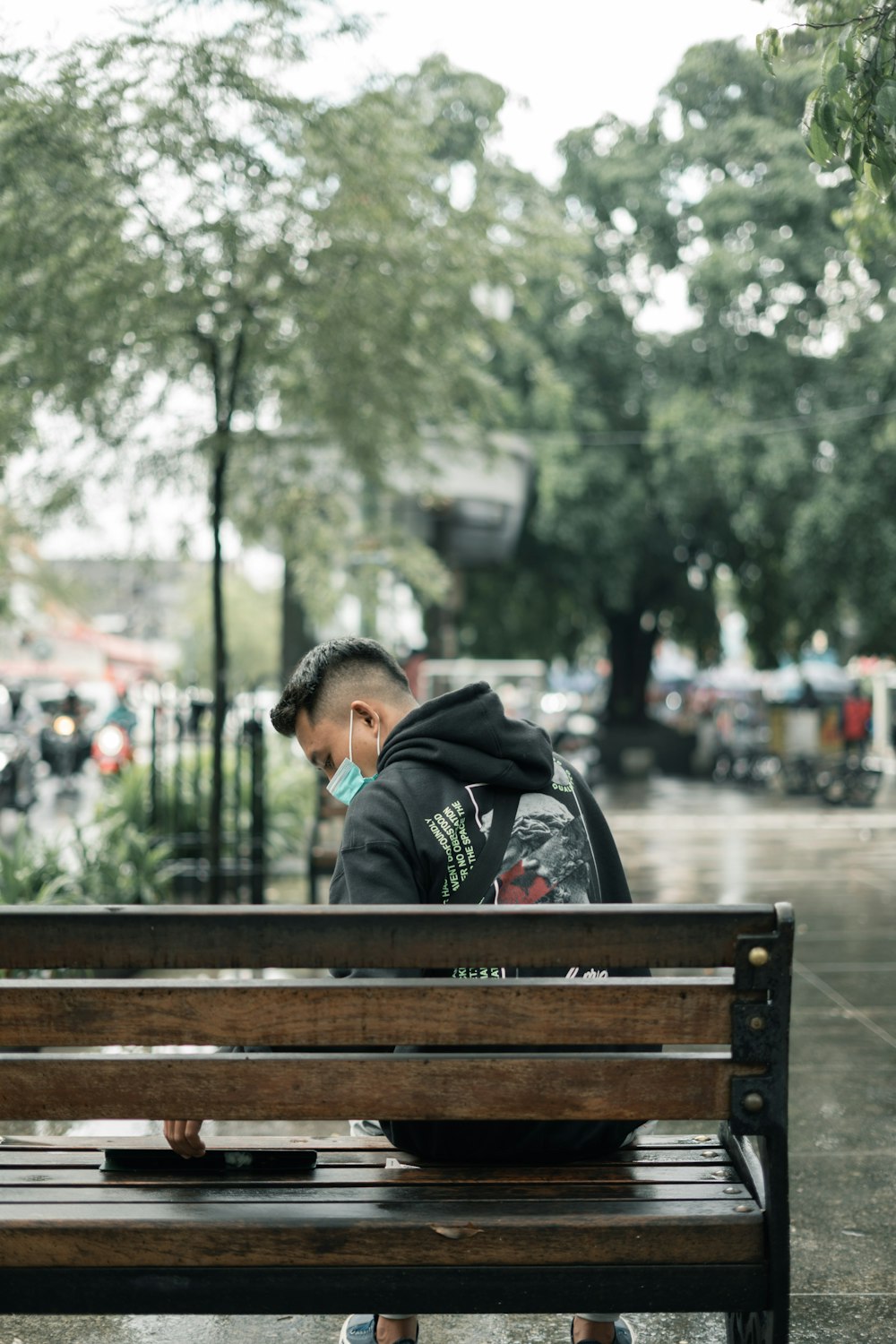Eine Person, die im Regen auf einer Bank sitzt