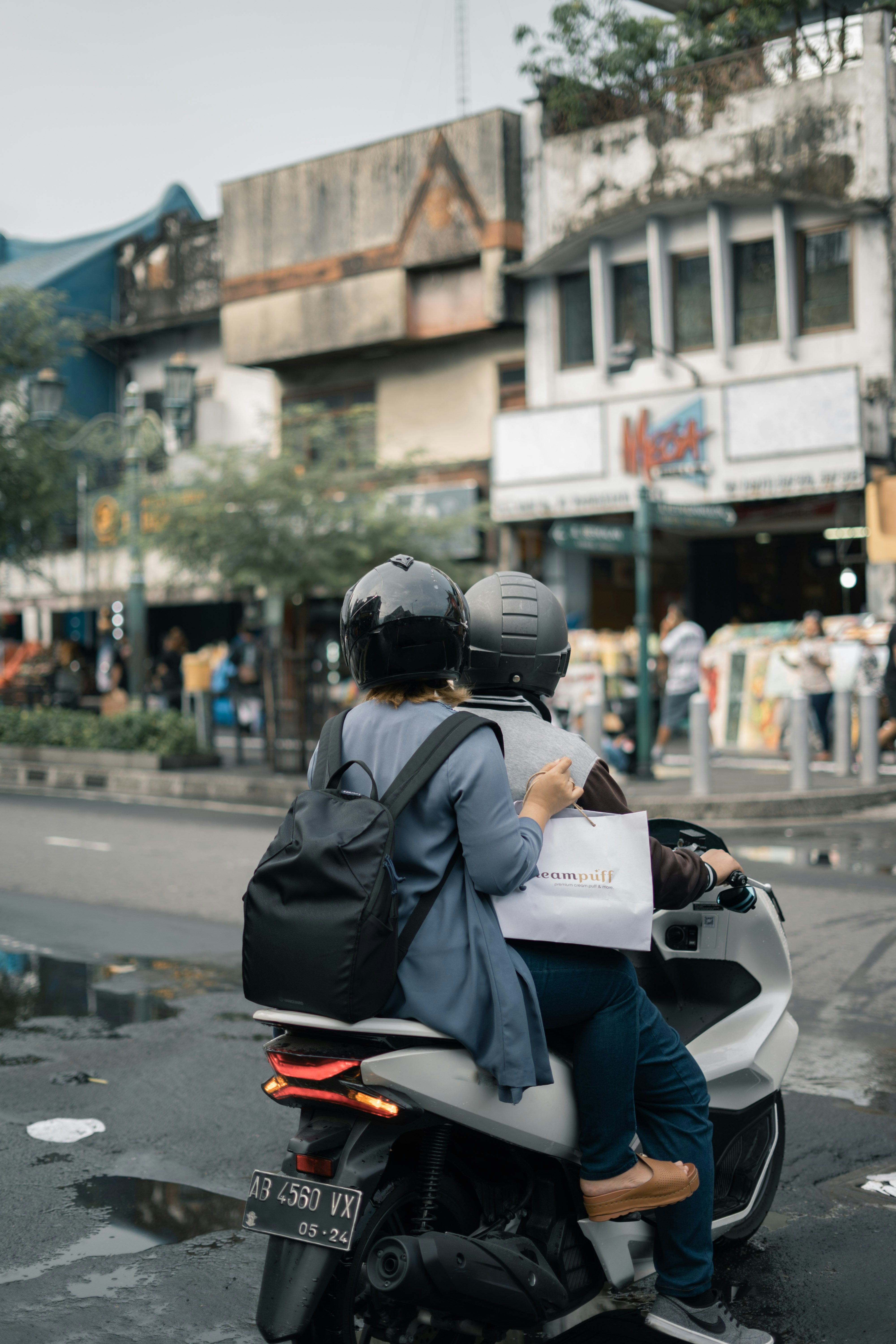 a man and a woman riding a motorcycle down a street