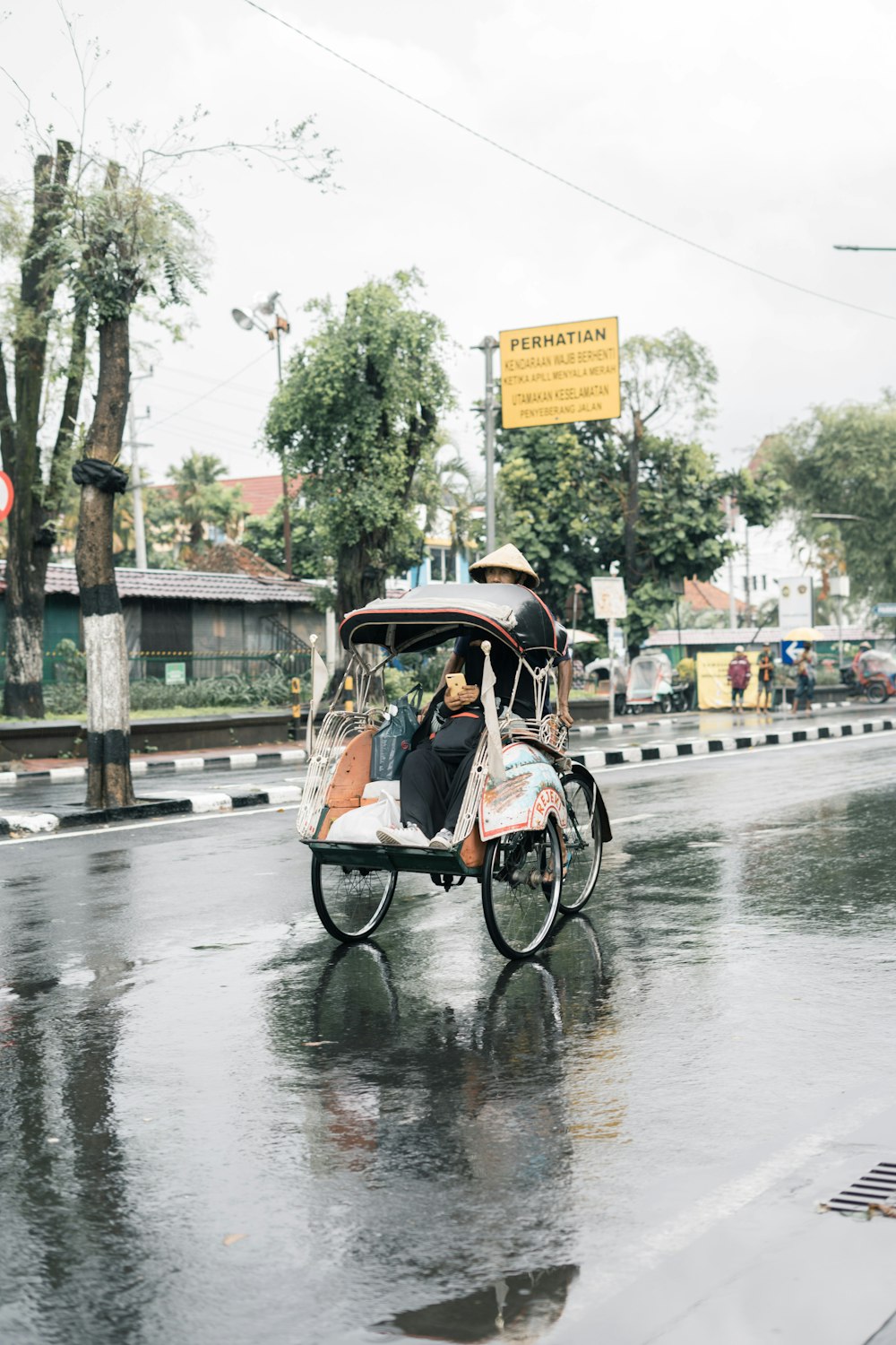 a man riding a rickshaw down a rain soaked street