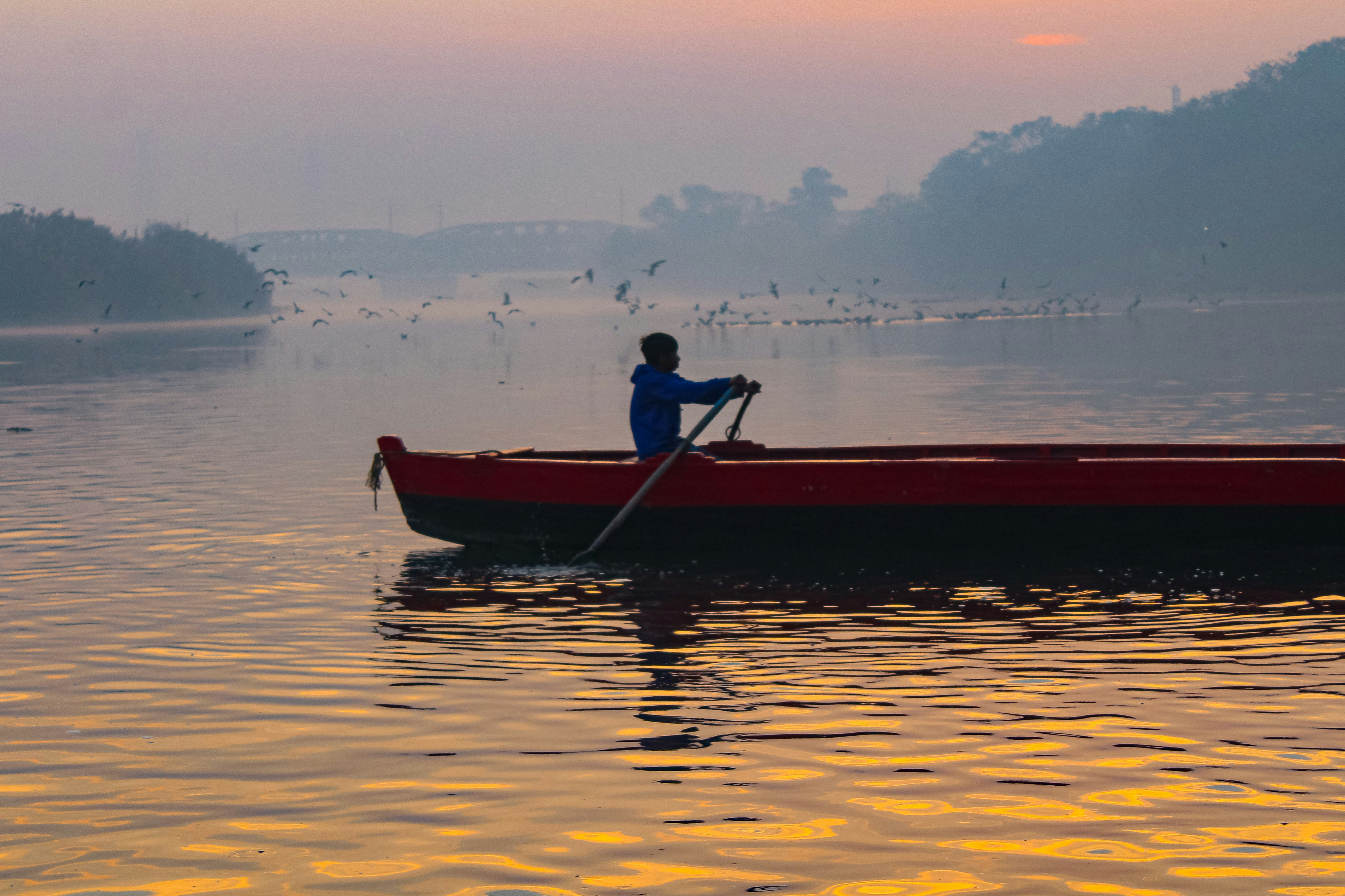 a person in a red boat on a body of water, 