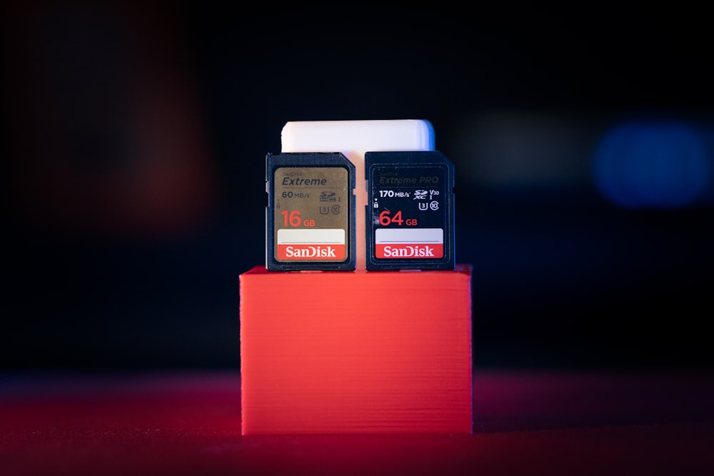 a couple of cell phones sitting on top of a red stand