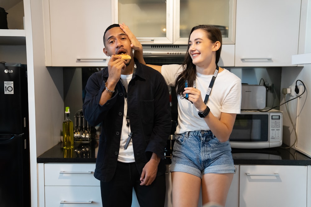 a man and a woman eating food in a kitchen