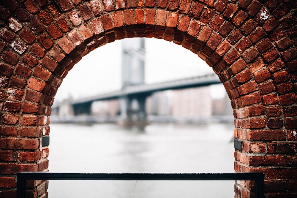 a brick arch with a bridge in the background