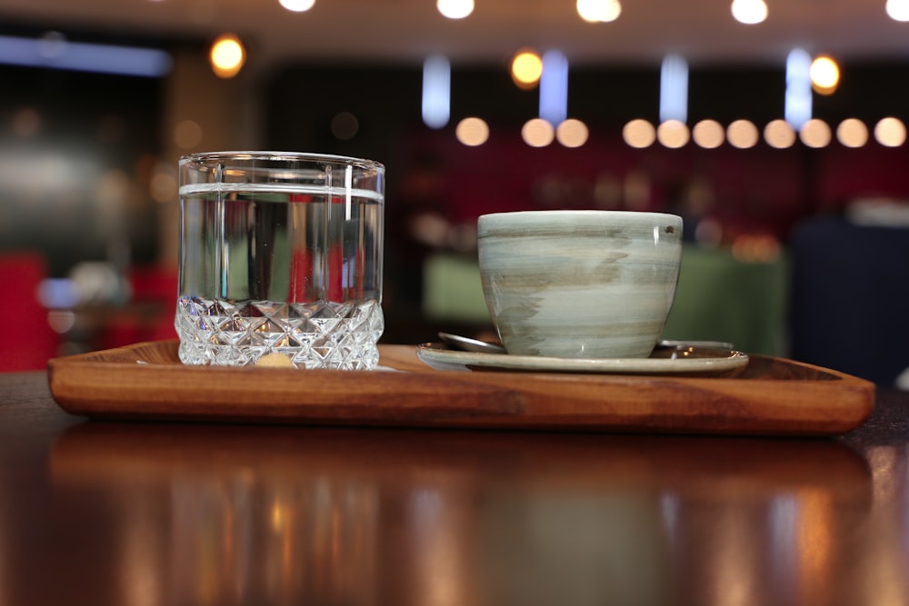 a glass of water and a bowl on a wooden tray
