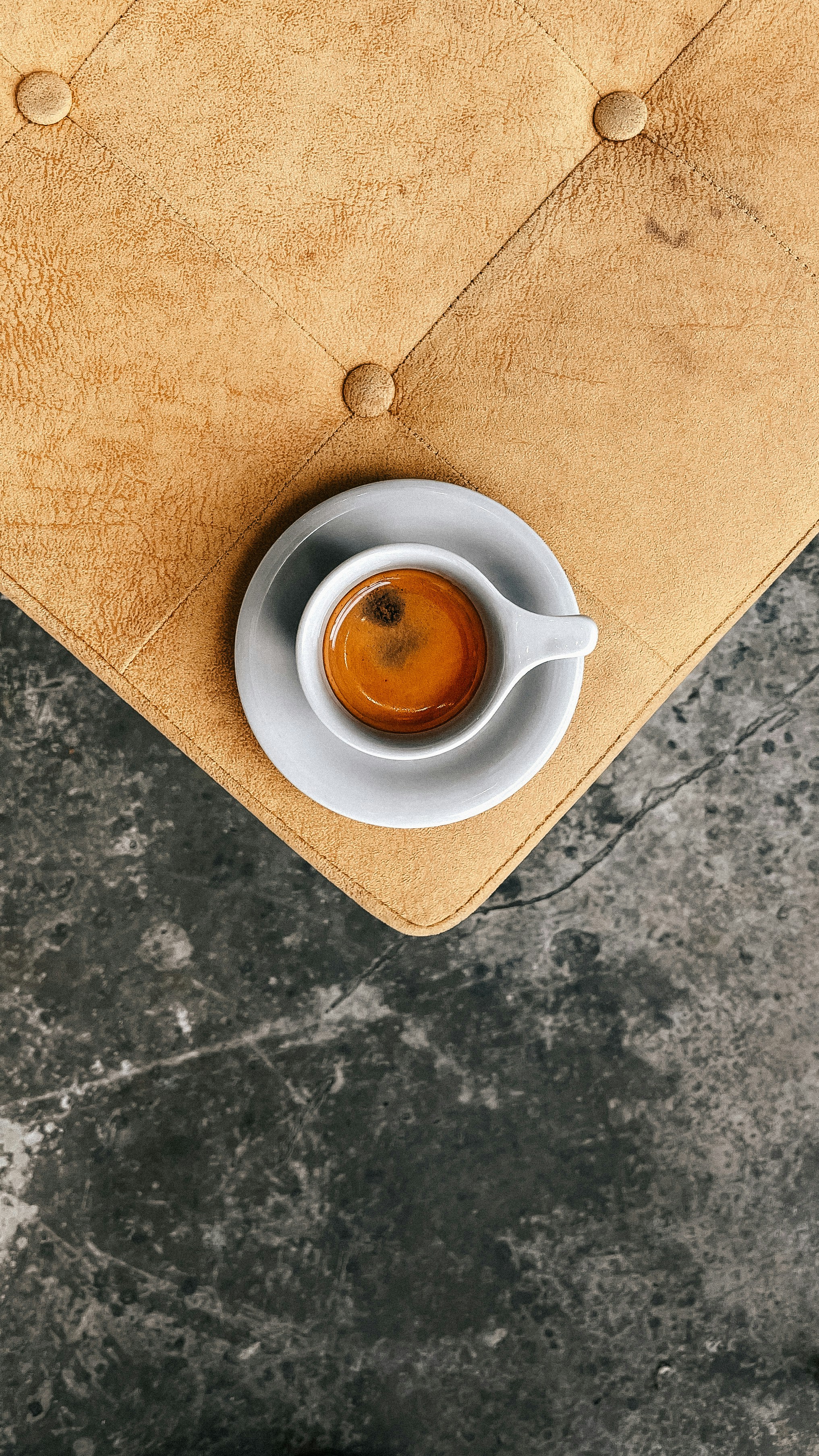 Rich espresso shot in a small ceramic cup with golden crema on a dark wooden surface