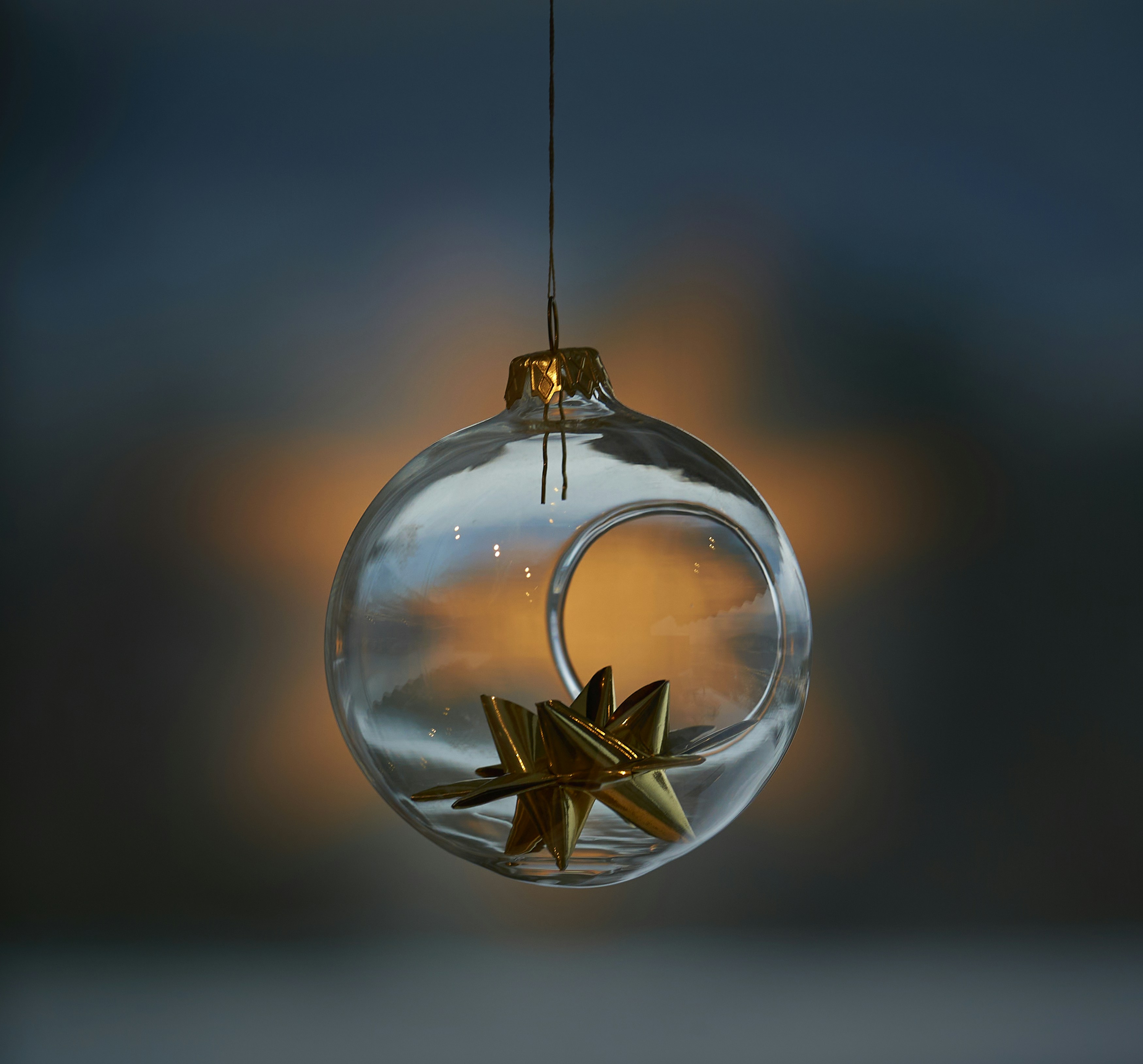a glass ornament with a gold star hanging from it