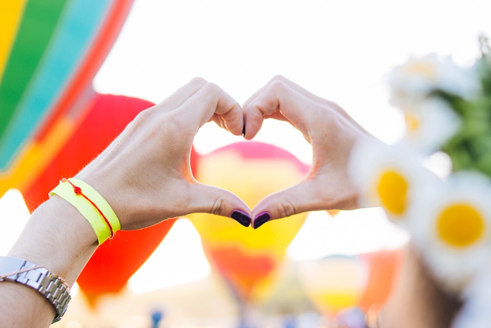 two people making a heart shape with their hands