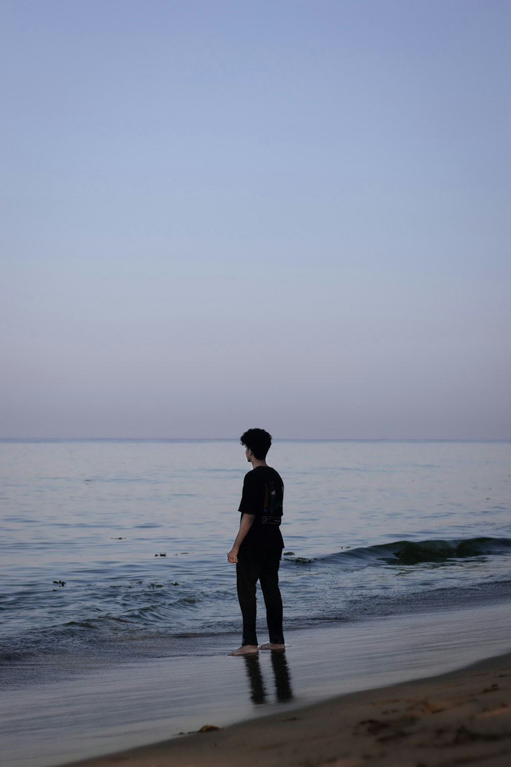 a person standing on a beach next to the ocean