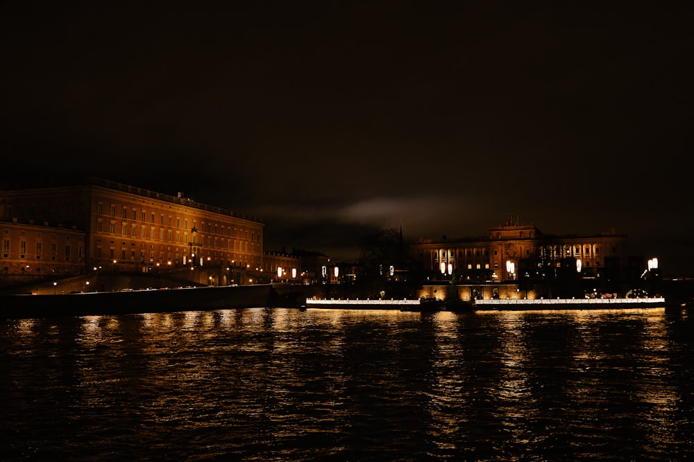 a large body of water at night with buildings in the background