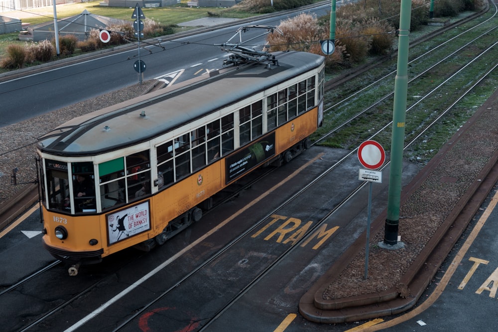 a yellow tram is going down the tracks