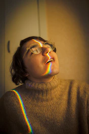 a woman with glasses and a rainbow sweater
