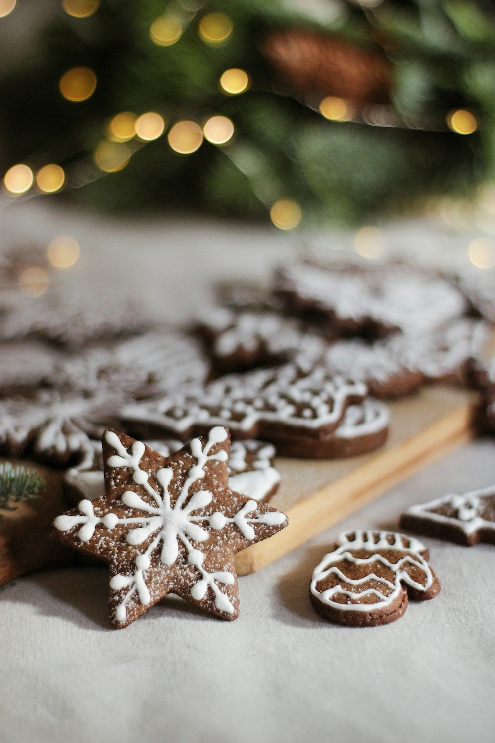 a close up of a tray of cookies near a christmas tree