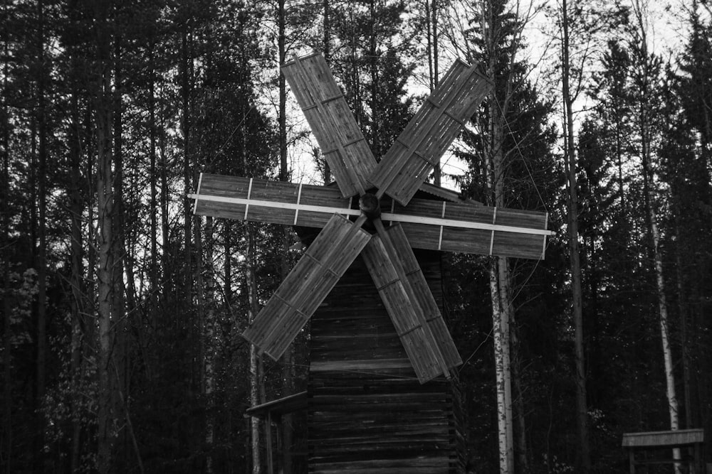 a black and white photo of a windmill in the woods