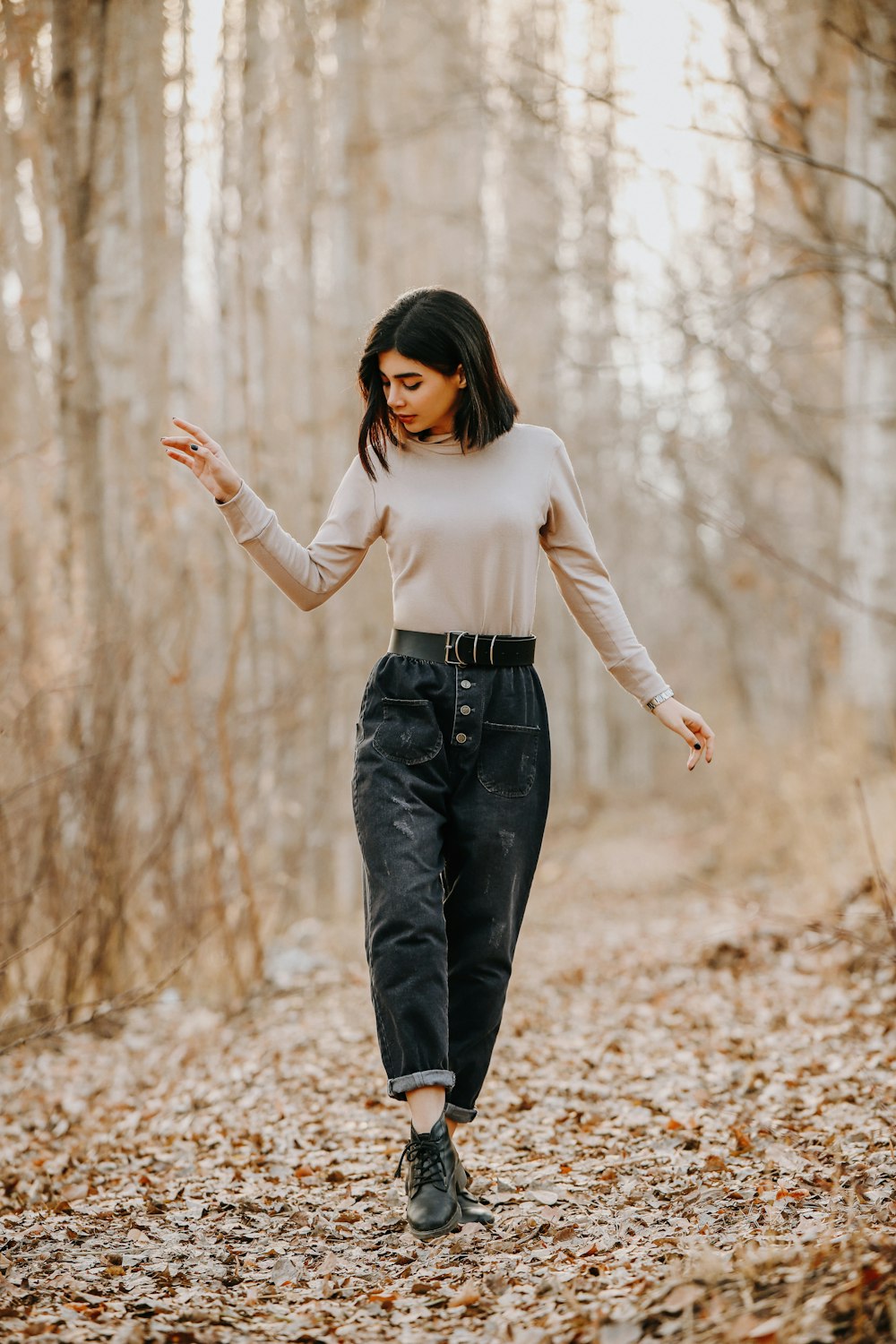 a woman walking through a leaf covered forest