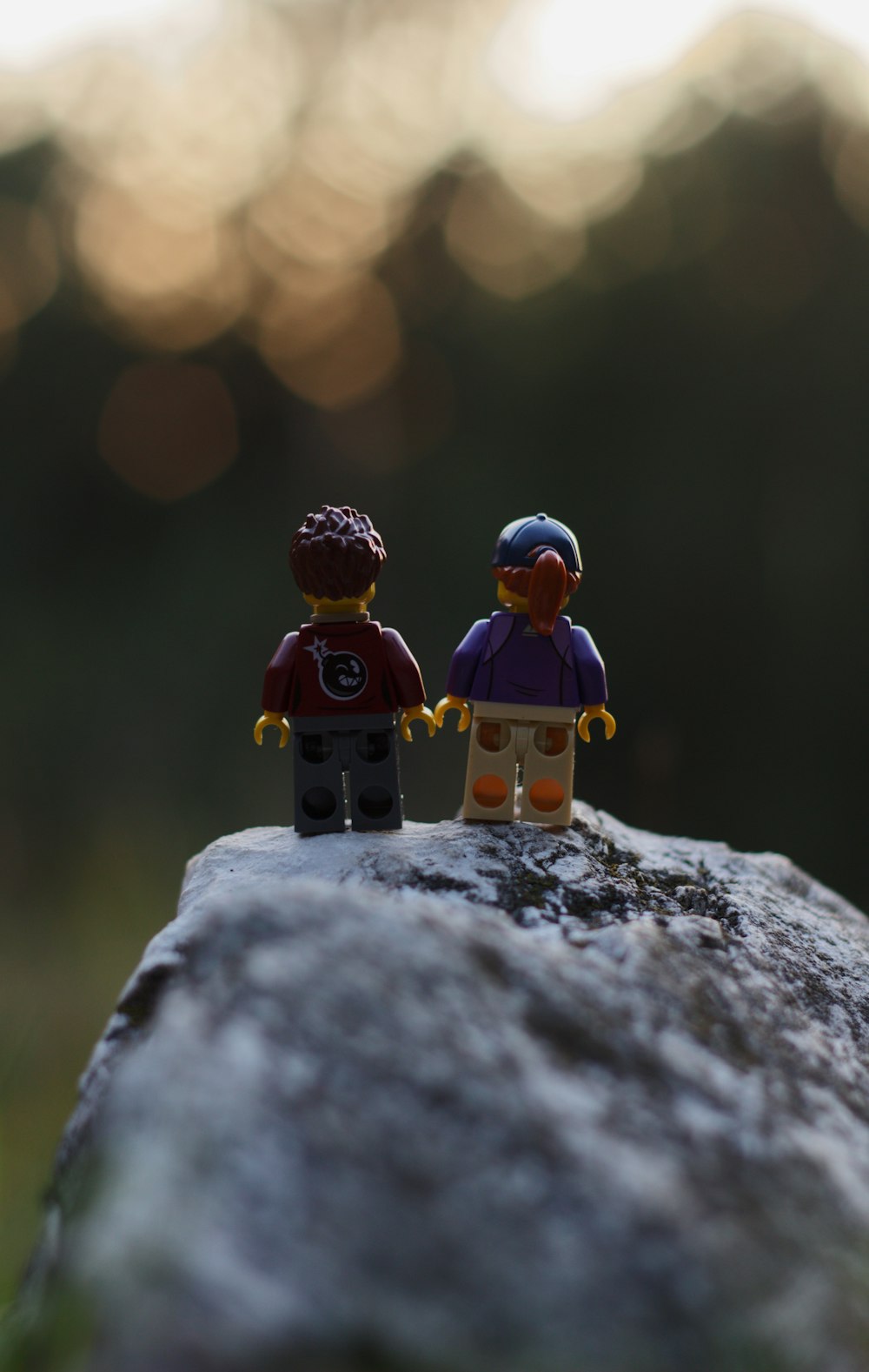 a couple of small figurines sitting on top of a rock