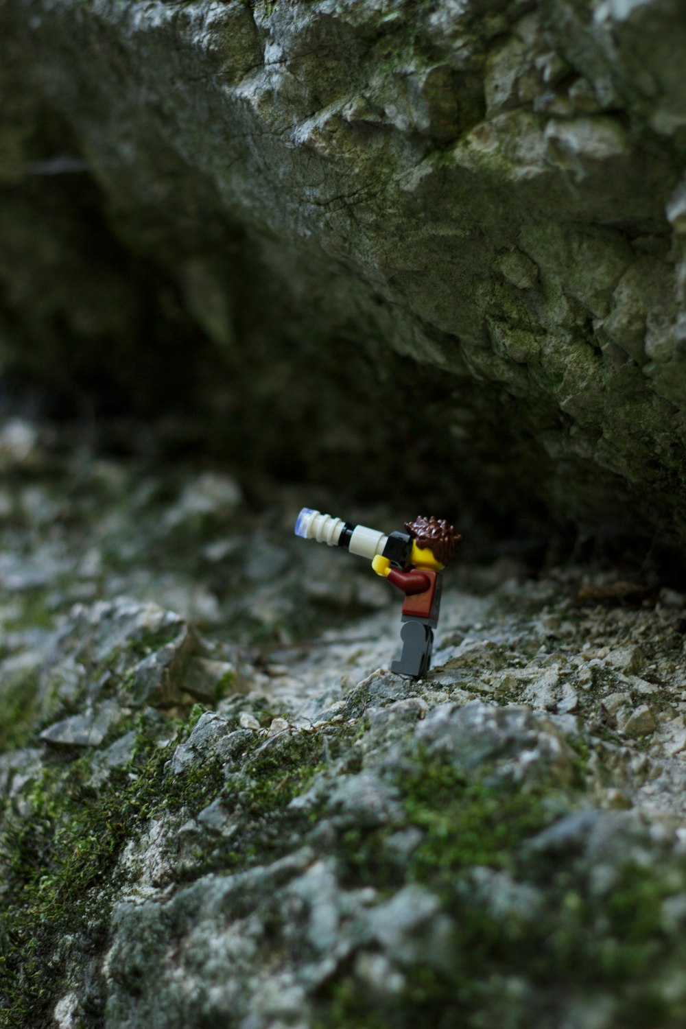 a lego man with a telescope on a rock