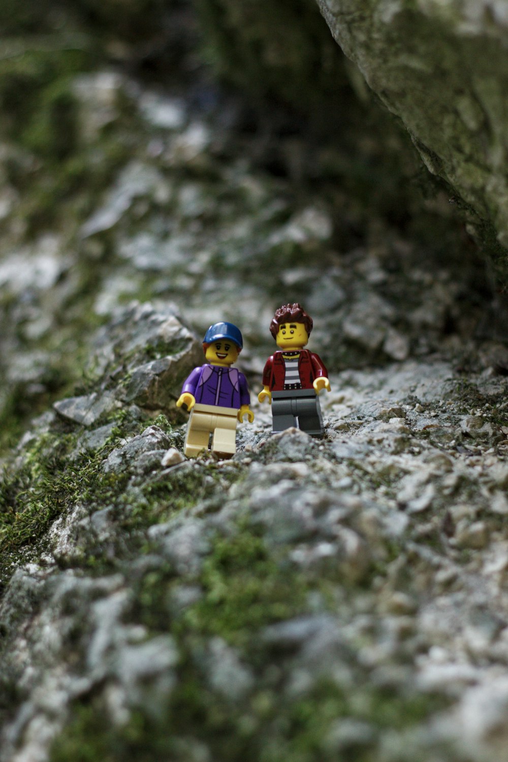a couple of legos standing on top of a rock