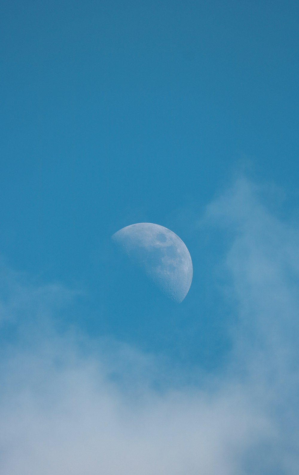 a half moon in a blue sky with clouds